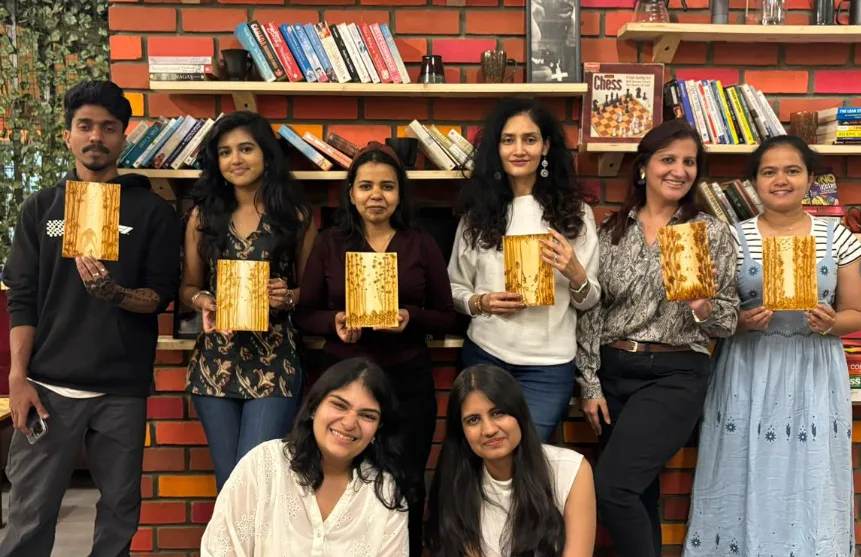 Guests holding books together in front of the café bookshelves.