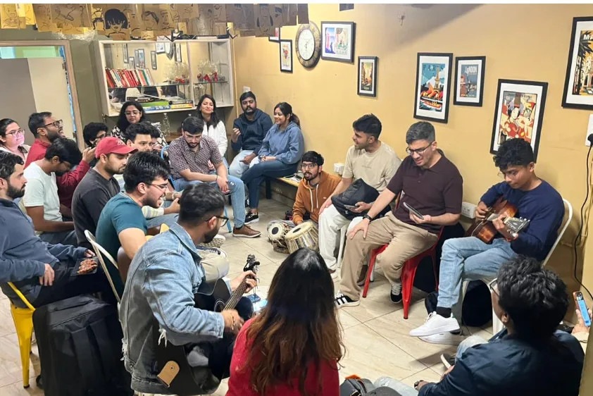 A community music gathering with guests playing guitar and percussion.