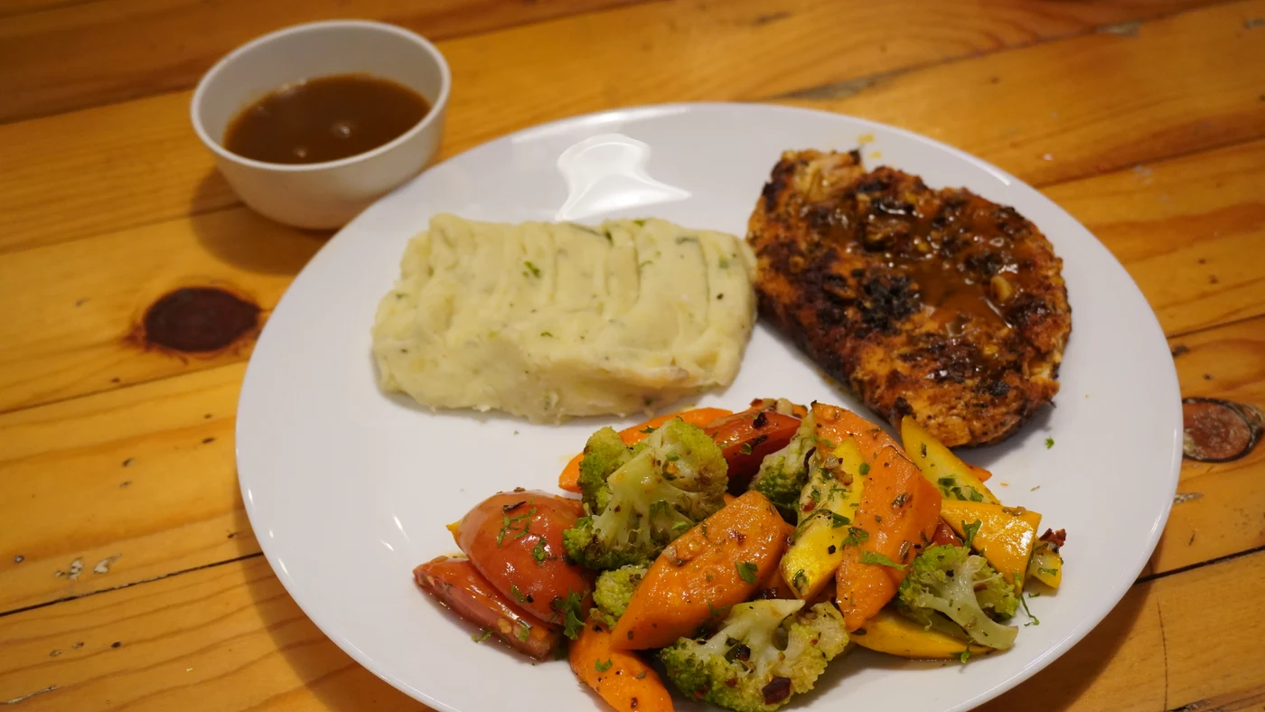 Grilled chicken, mashed potatoes and vegetables served on a white plate at Story Coffee House